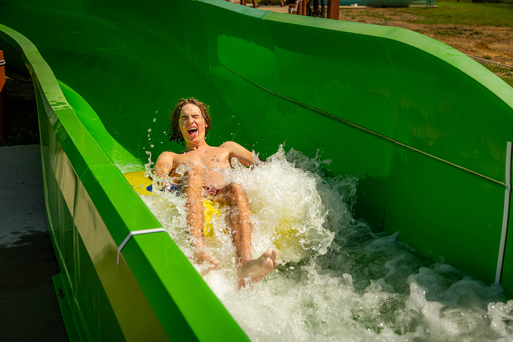 Older boy green slide red shorts